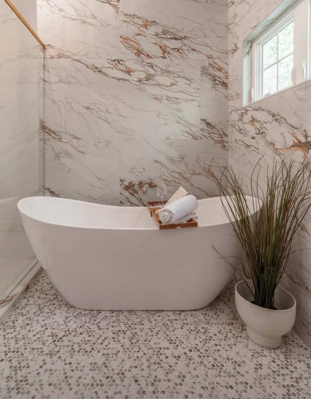 Primary bathroom finished in book-matched marble with a freestanding soaking tub