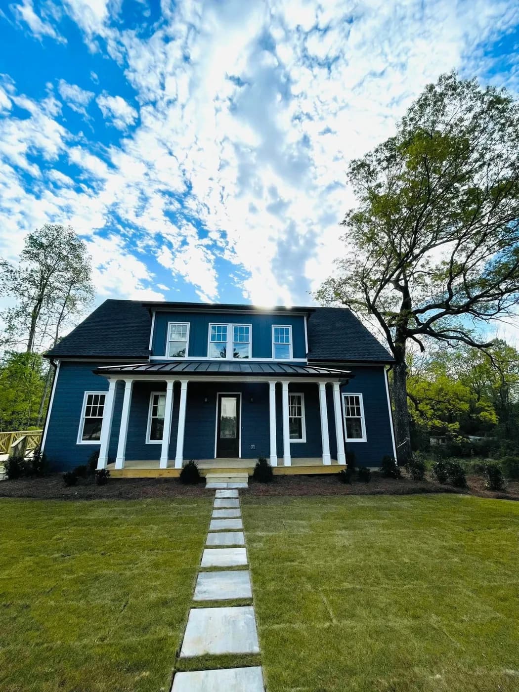 Navy blue two-story colonial with a white columned porch and a flagstone walkway