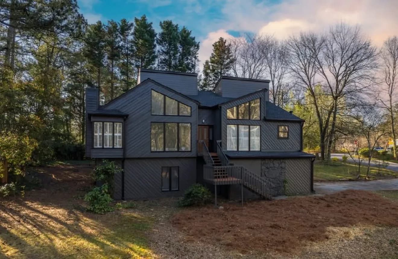 Contemporary dark-clad home with full-height glazing set among bare winter trees
